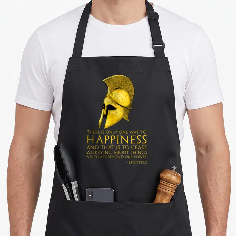 Tablier de cuisine noir avec casque spartate doré et texte jaune sur la philosophie stoïque.