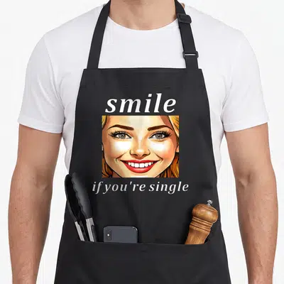Tablier de cuisine noir avec illustration d'un visage souriant et texte blanc Smile if you're single.
