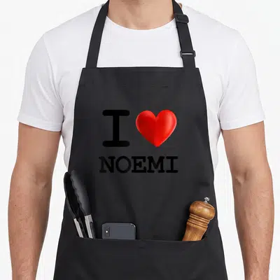 Tablier de cuisine noir avec inscription I Love Noemi et un grand cœur rouge brillant au centre du motif imprimé.