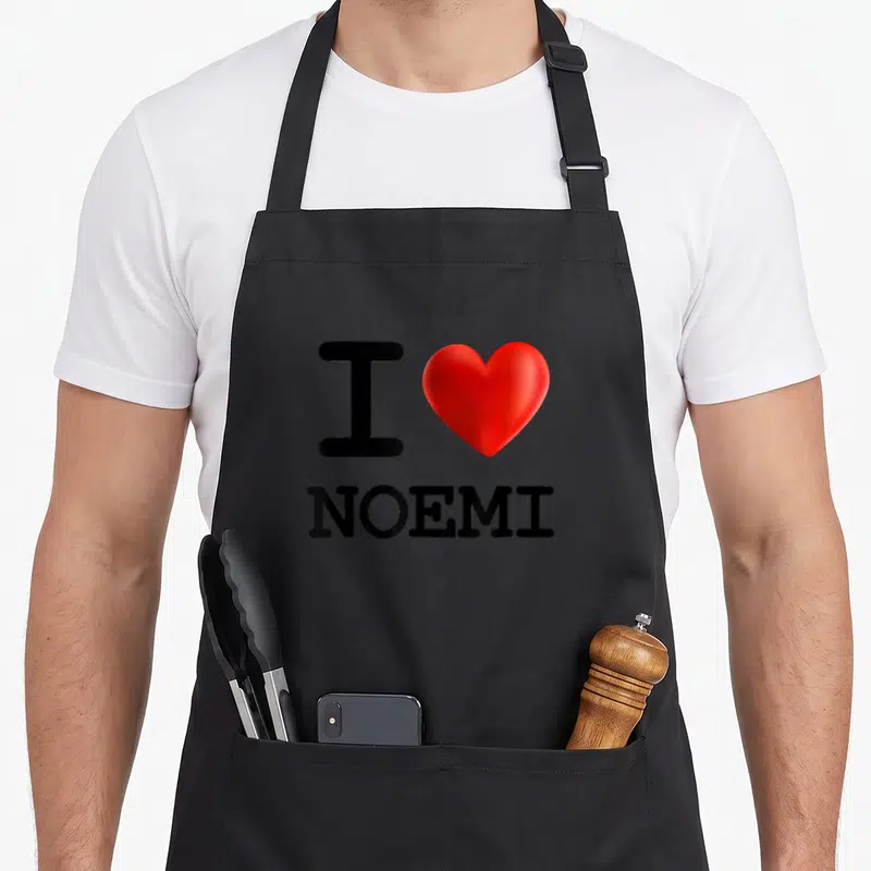 Tablier de cuisine noir avec inscription I Love Noemi et un grand cœur rouge brillant au centre du motif imprimé.