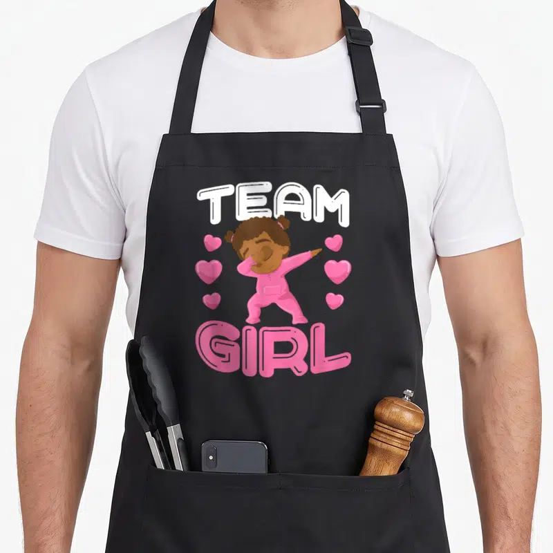 Tablier de cuisine noir avec une illustration rose d'une enfant faisant un dab sous les mots Team Girl.