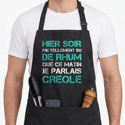 Tablier de cuisine noir avec inscription humoristique en lettres turquoise et blanches sur fond uni.
