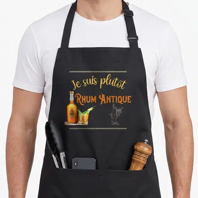 Tablier de cuisine noir avec une bouteille de rhum, un verre à cocktail et l'inscription Je suis plutôt rhum antique en lettres dorées et orange.