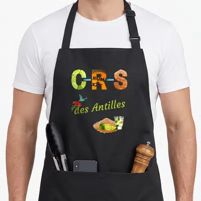 Tablier de cuisine noir avec motif CRS des Antilles illustré par du citron, du rhum et un cocktail tropical.