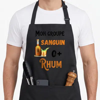 Tablier de cuisine noir avec illustration bouteille rhum verre éclaboussant et texte Mon groupe sanguin O+ Rhum en orange et noir.