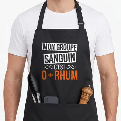 Tablier de cuisine noir avec inscription Mon groupe sanguin c'est 0 plus Rhum en orange et blanc.