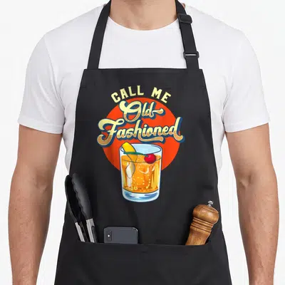 Tablier de cuisine noir avec illustration vintage d'un cocktail Old Fashioned et du texte Call Me Old Fashioned en lettres jaunes.