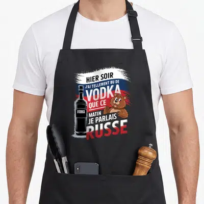 Tablier de cuisine noir avec illustration d'une bouteille de vodka, d'un ours et texte humoristique sur fond tricolore.