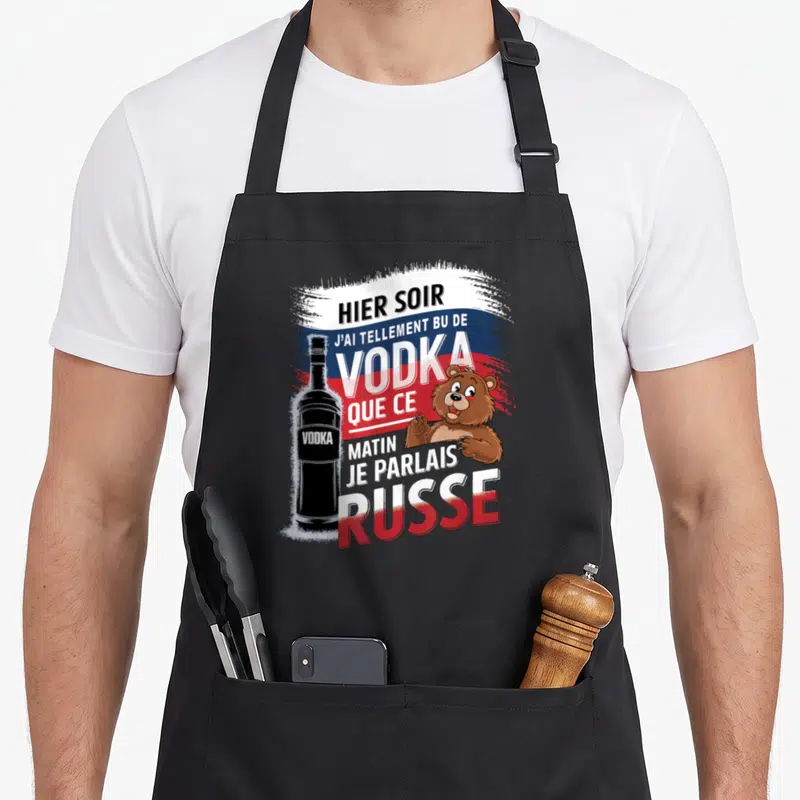 Tablier de cuisine noir avec illustration d'une bouteille de vodka, d'un ours et texte humoristique sur fond tricolore.
