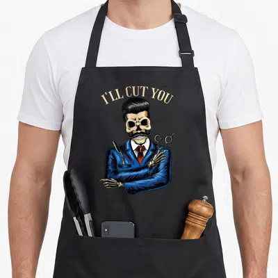 Tablier de cuisine noir avec squelette barbier en costume bleu tenant ciseaux et rasoir, texte I'll cut you au-dessus.