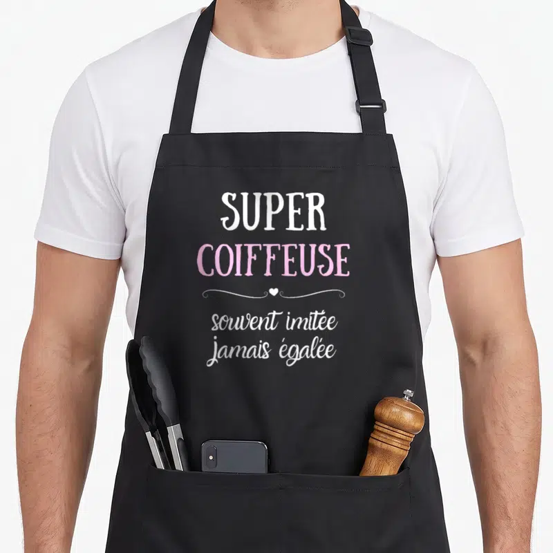 Tablier de cuisine noir avec inscription Super coiffeuse souvent imitée jamais égalée en rose et blanc.