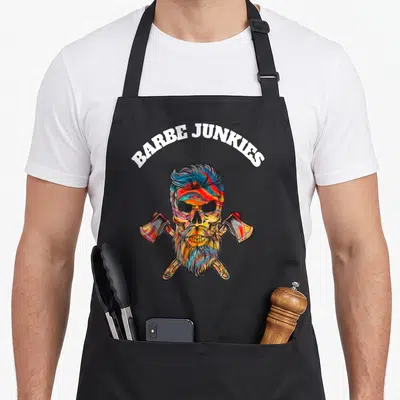 Tablier de cuisine noir avec un crâne barbu coloré surmonté du texte Barbe Junkies et deux haches croisées.