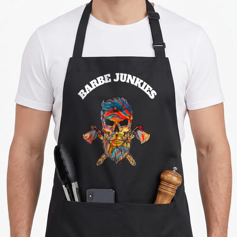 Tablier de cuisine noir avec un crâne barbu coloré surmonté du texte Barbe Junkies et deux haches croisées.