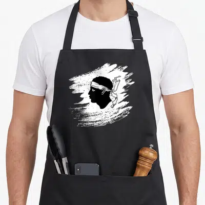 Tablier de cuisine noir avec une tête de Maure blanche et le texte Corssica Corsu France.