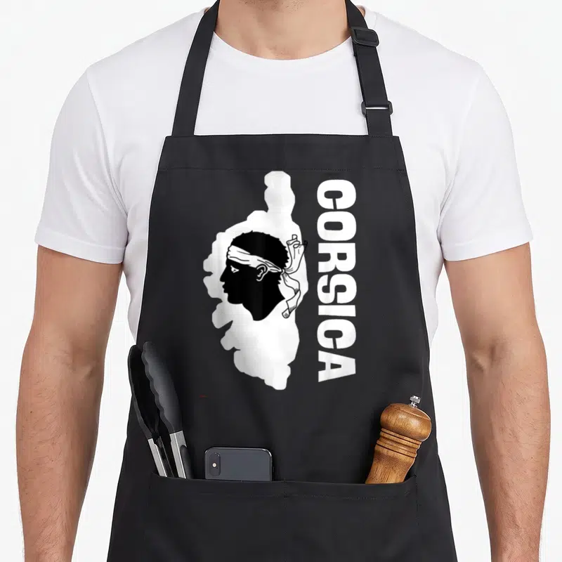 Tablier de cuisine noir avec une tête de maure blanche et le texte vertical CORSICA