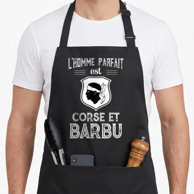 Tablier de cuisine noir avec illustration tête de Maure et texte blanc L'homme parfait est Corse et barbu