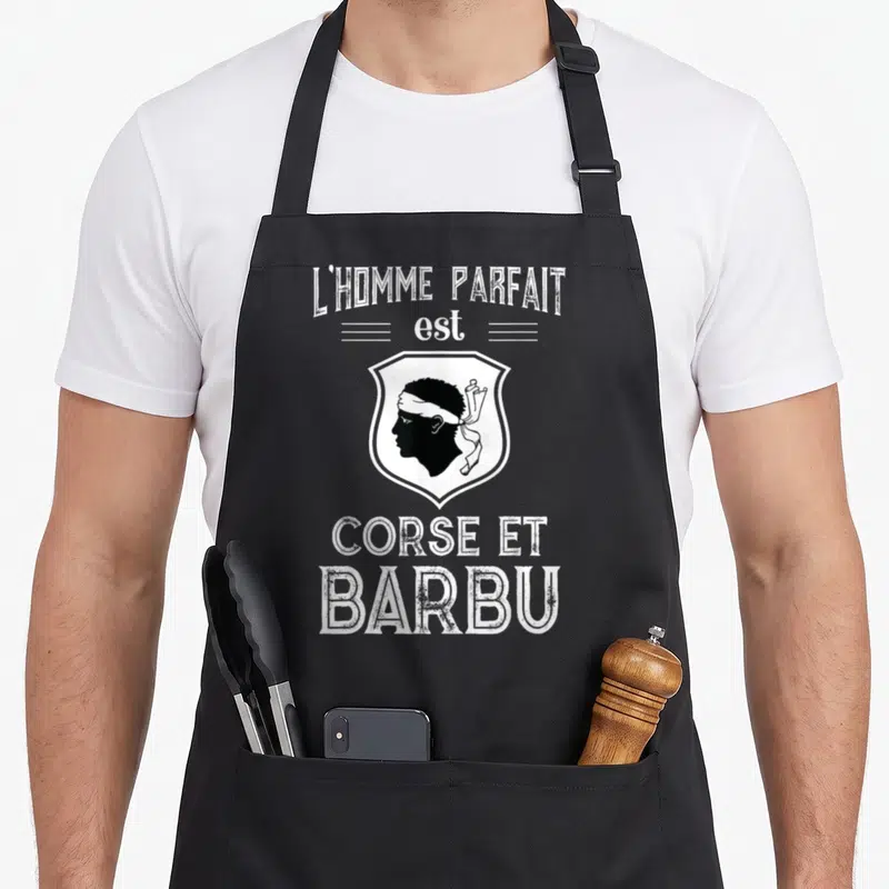 Tablier de cuisine noir avec illustration tête de Maure et texte blanc L'homme parfait est Corse et barbu