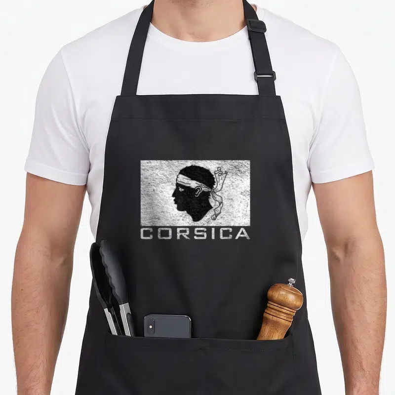 Tablier de cuisine noir avec illustration Mor's Head et inscription CORSICA en blanc texturé.