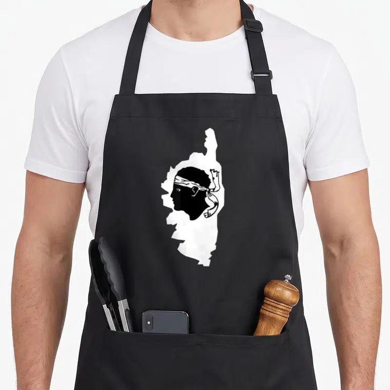Tablier de cuisine noir avec silhouette blanche de l'île Corsica intégrant un profil de pirate au bandana.