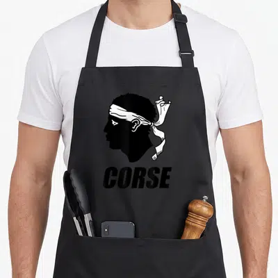 Tablier de cuisine noir avec profil Maure blanc et le mot CORSE en lettres noires audacieuses.