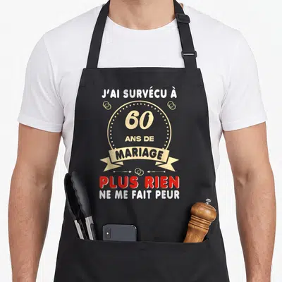 Tablier de cuisine noir avec inscription J'ai survécu à 60 ans de mariage et anneaux dorés sur fond gris uni.