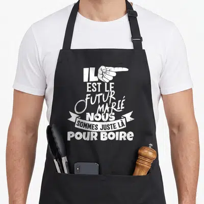 Tablier de cuisine noir avec main blanche pointant vers le texte Il est le futur marié nous sommes juste là pour boire.