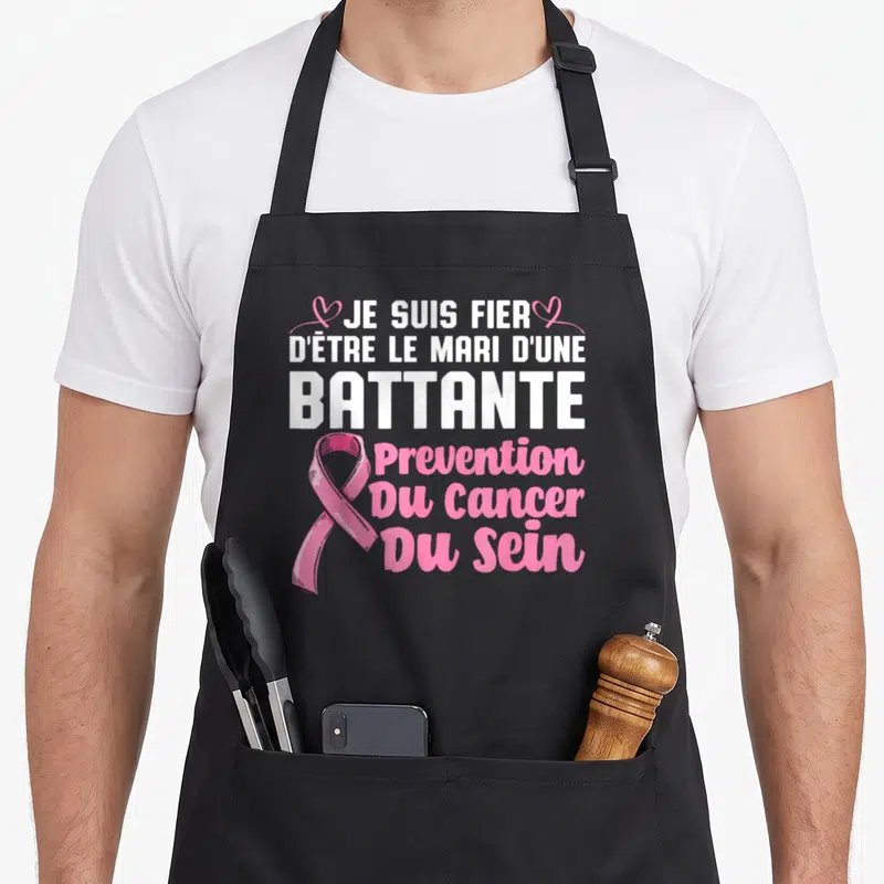 Tablier de cuisine noir avec inscription blanche et ruban rose symbolisant la lutte contre le cancer du sein.