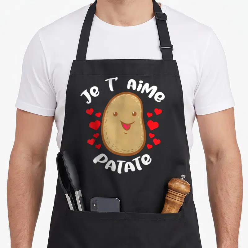 Tablier de cuisine noir avec une patate souriante entourée de cœurs rouges et du texte Je T'aime Patate