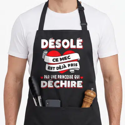 Tablier de cuisine noir avec inscription humoristique sur cœur rouge et bandeau blanc proclamant un mariage heureux.