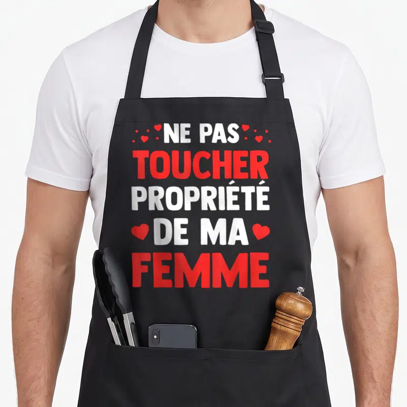 Tablier de cuisine noir avec l'inscription Ne pas toucher propriété de ma femme en rouge et blanc entouré de petits cœurs.