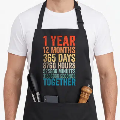 Tablier de cuisine noir avec inscription 1 year 12 months 365 days together en lettres dégradées.