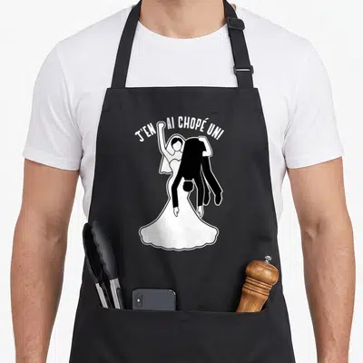 Tablier de cuisine noir avec une illustration d'une mariée portant un homme et le texte J'en ai chopé un