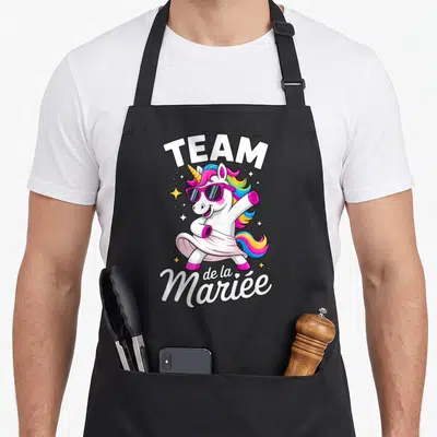 Tablier de cuisine noir avec licorne rose portant des lunettes de soleil et le texte Team de la Mariée.