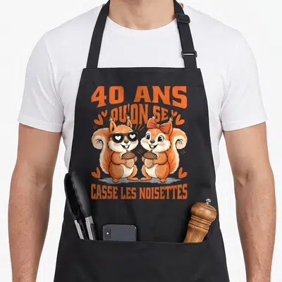 Tablier de cuisine noir avec deux écureuils orange tenant des noix et le texte 40 ans qu'on se casse les noisettes.