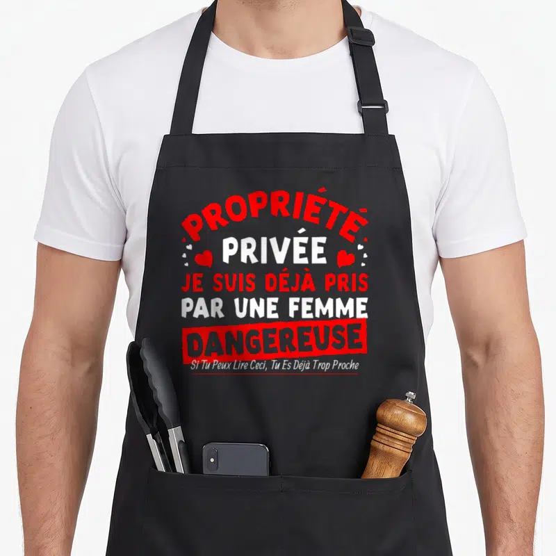 Tablier de cuisine noir avec inscription rouge et blanche Propriété privée Je suis déjà pris par une femme dangereuse entouré de petits cœurs rouges.