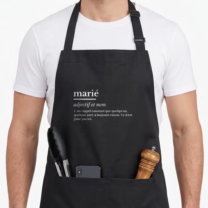 Tablier de cuisine noir avec définition humoristique du mot marié en typographie blanche.