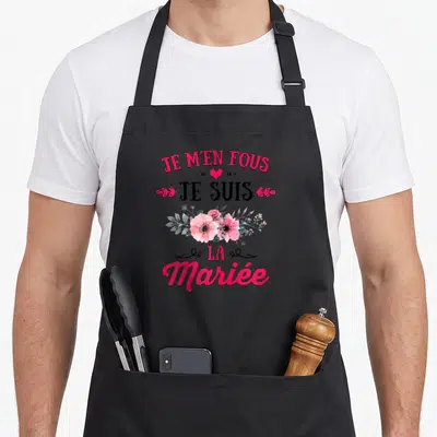 Tablier de cuisine noir avec inscription Je m'en Fous Je Suis La Mariée et bouquet floral rose.