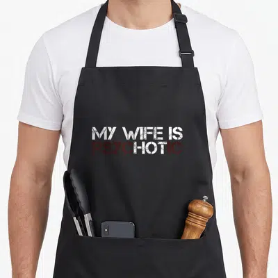 Tablier de cuisine noir avec l'inscription My Wife Is Psychotic en lettres blanches et bordeaux style pochoir.