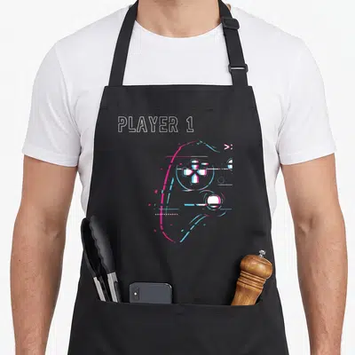 Tablier de cuisine noir avec manette de jeu vidéo néon rose et bleu et texte Player 1