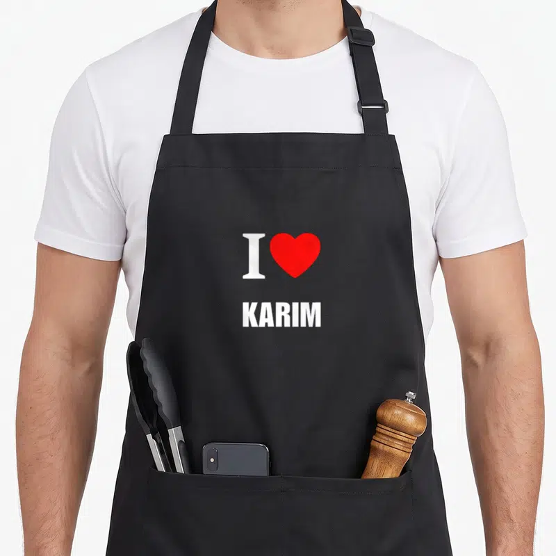 Tablier de cuisine noir avec l'inscription blanche I love Karim et un grand cœur rouge au centre du dos.