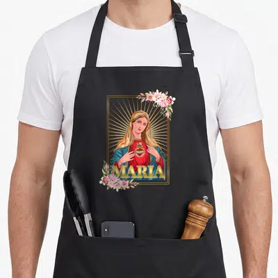 Tablier de cuisine noir avec une illustration colorée de la Vierge Marie, des fleurs roses et le mot MARIA en lettres dorées.