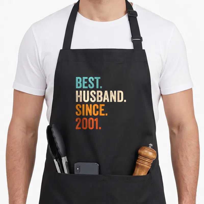 Tablier de cuisine noir avec le texte coloré Best Husband Since 2001 imprimé au centre.