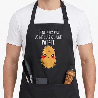 Tablier de cuisine noir avec une patate rose aux yeux brillants et le texte Je ne suis qu'une patate en lettres blanches.