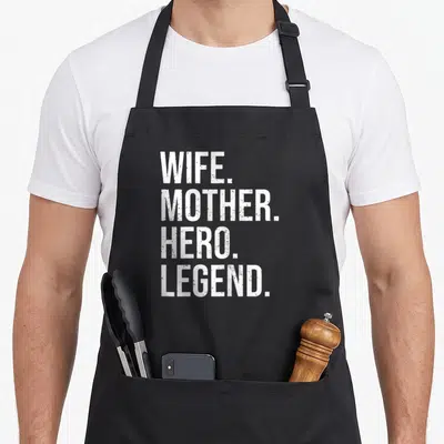 Tablier de cuisine noir avec l'inscription Wife Mother Hero Legend en lettres blanches verticales.