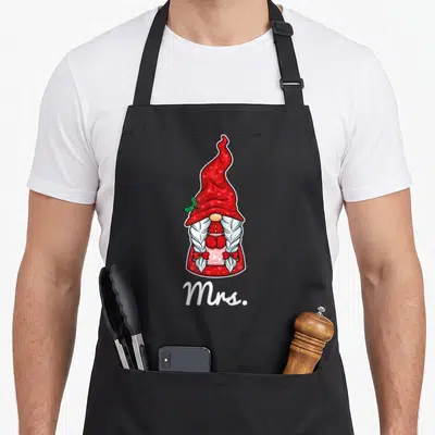 Tablier de cuisine noir avec illustration de gnome féminin Mrs. au chapeau rouge et tresses blanches.