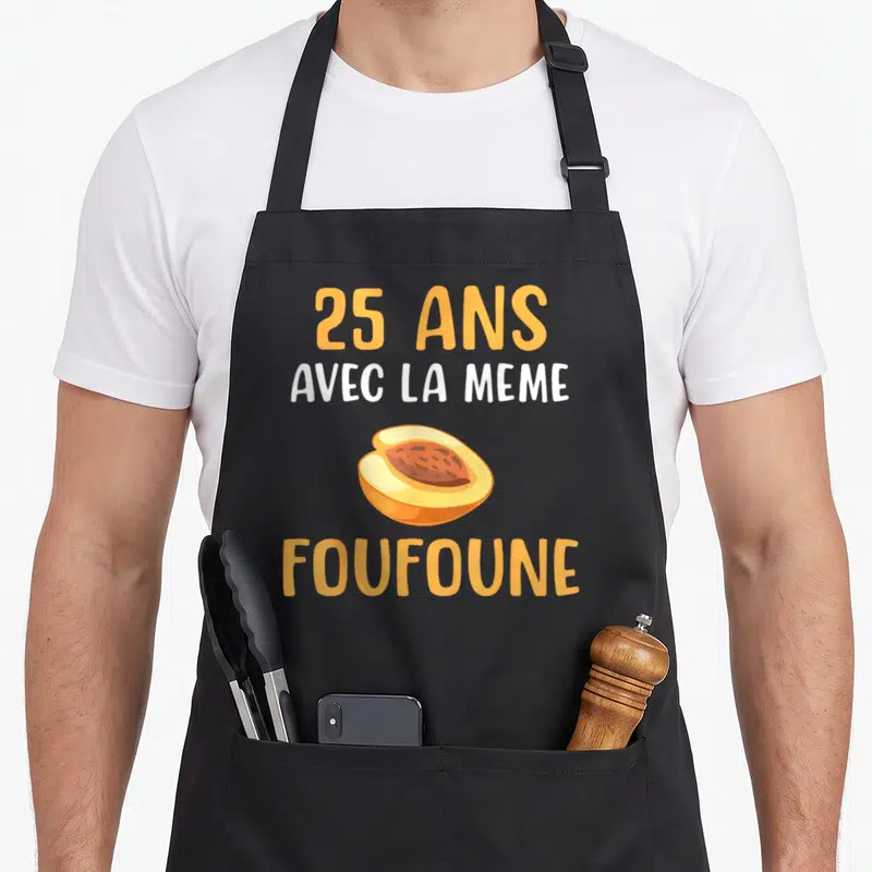 Tablier de cuisine noir avec l'inscription 25 ans avec la même foufoune et un dessin d'abricot coupé en deux au centre.