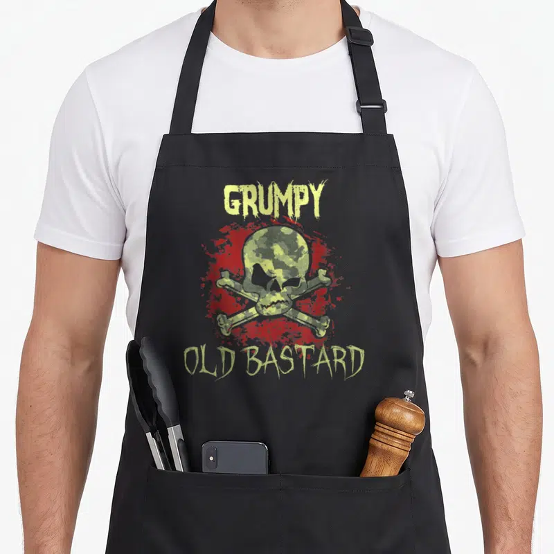 Tablier de cuisine noir avec un crâne en camouflage rouge et le texte Grumpy Old Bastard imprimé en jaune.