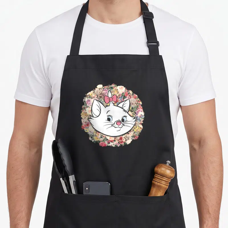 Tablier de cuisine noir avec le portrait de Marie entouré d'un bouquet floral coloré et d'un nœud rose.