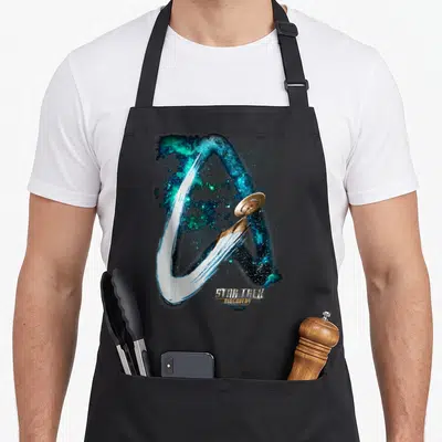 Tablier de cuisine noir avec un vaisseau spatial traversant une galaxie bleue et verte au style brushwork.
