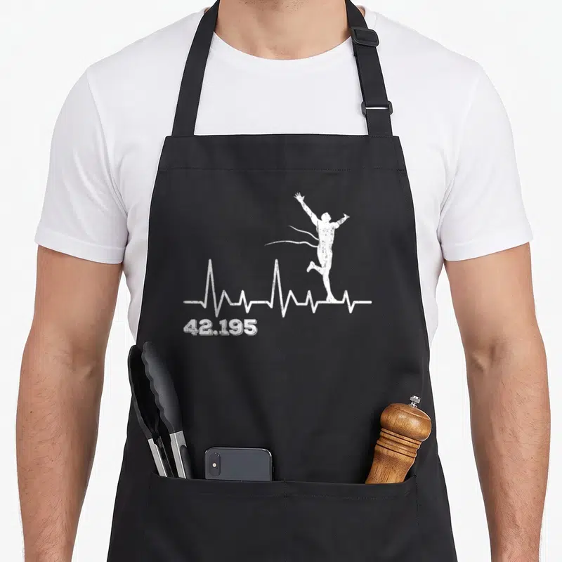 Tablier de cuisine noir avec silhouette blanche d'un coureur sur une ligne d'ECG et le chiffre 42.195 en bas à gauche.